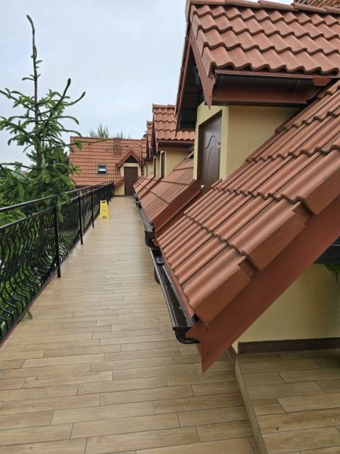 Długi balkon na piętrze, z którego wchodzi się do pokoi