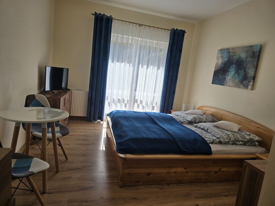 Pokój z drewnianym łóżkiem i granatową narzutą
